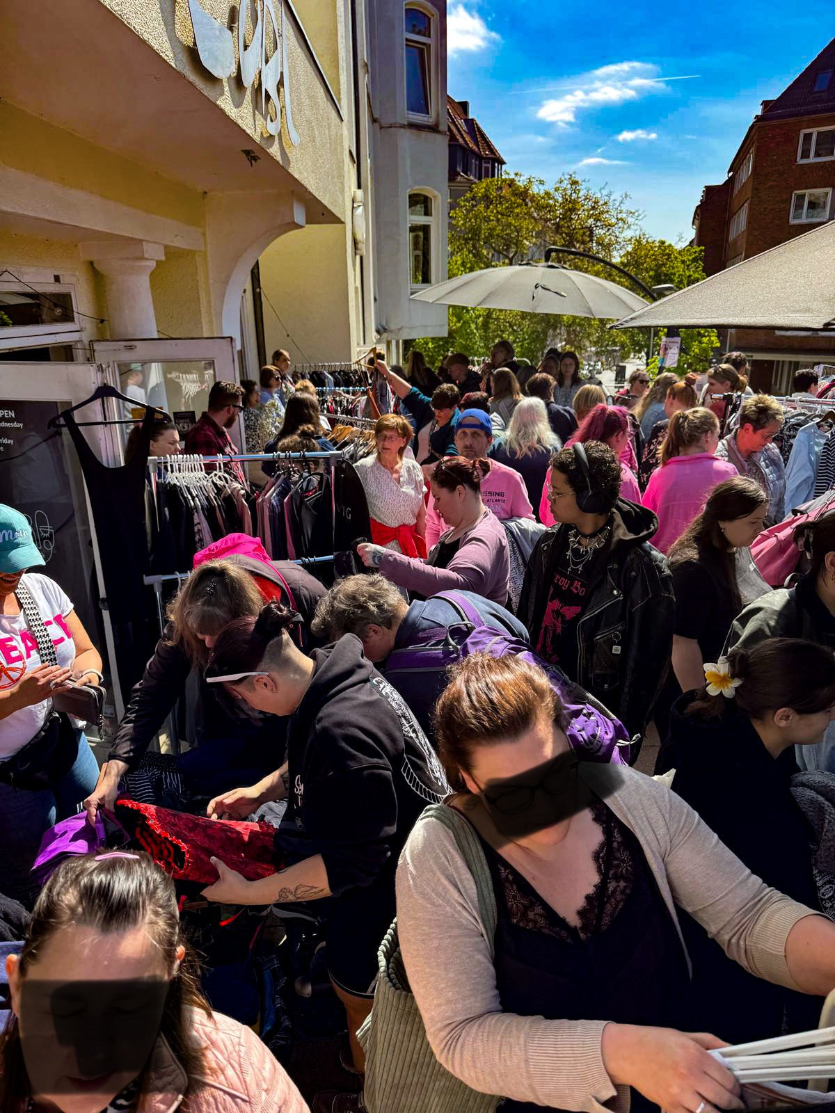 Bild des ersten Curvy Flohmarkts auf der Terrasse des Cobl in Kiel mit Ständen mit Kleidung und den vielen Besucher*innen